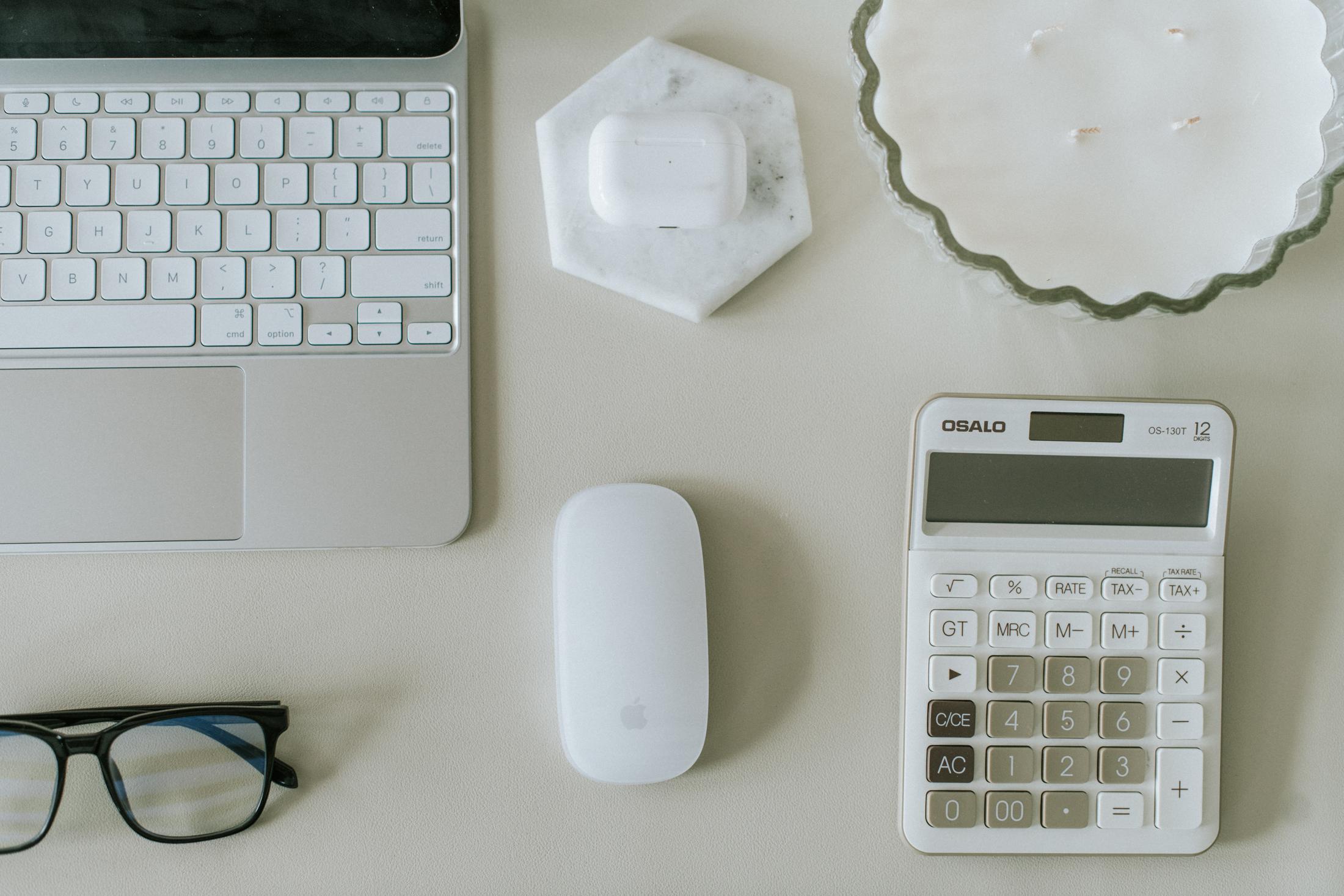 A desk with a calculator and laptop