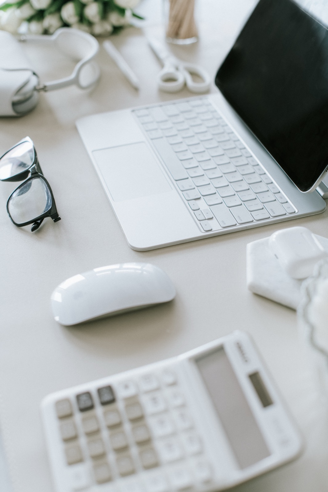 A tidy desk with a laptop, calculator and glasses
